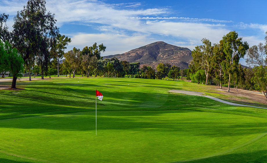 green golf course red flag with mountain in background